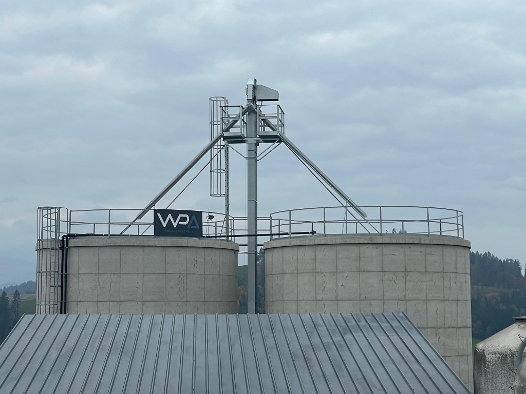 WPA-Betonsilos mit Förderanlage und WPA-Logo in grüner Hügellandschaft