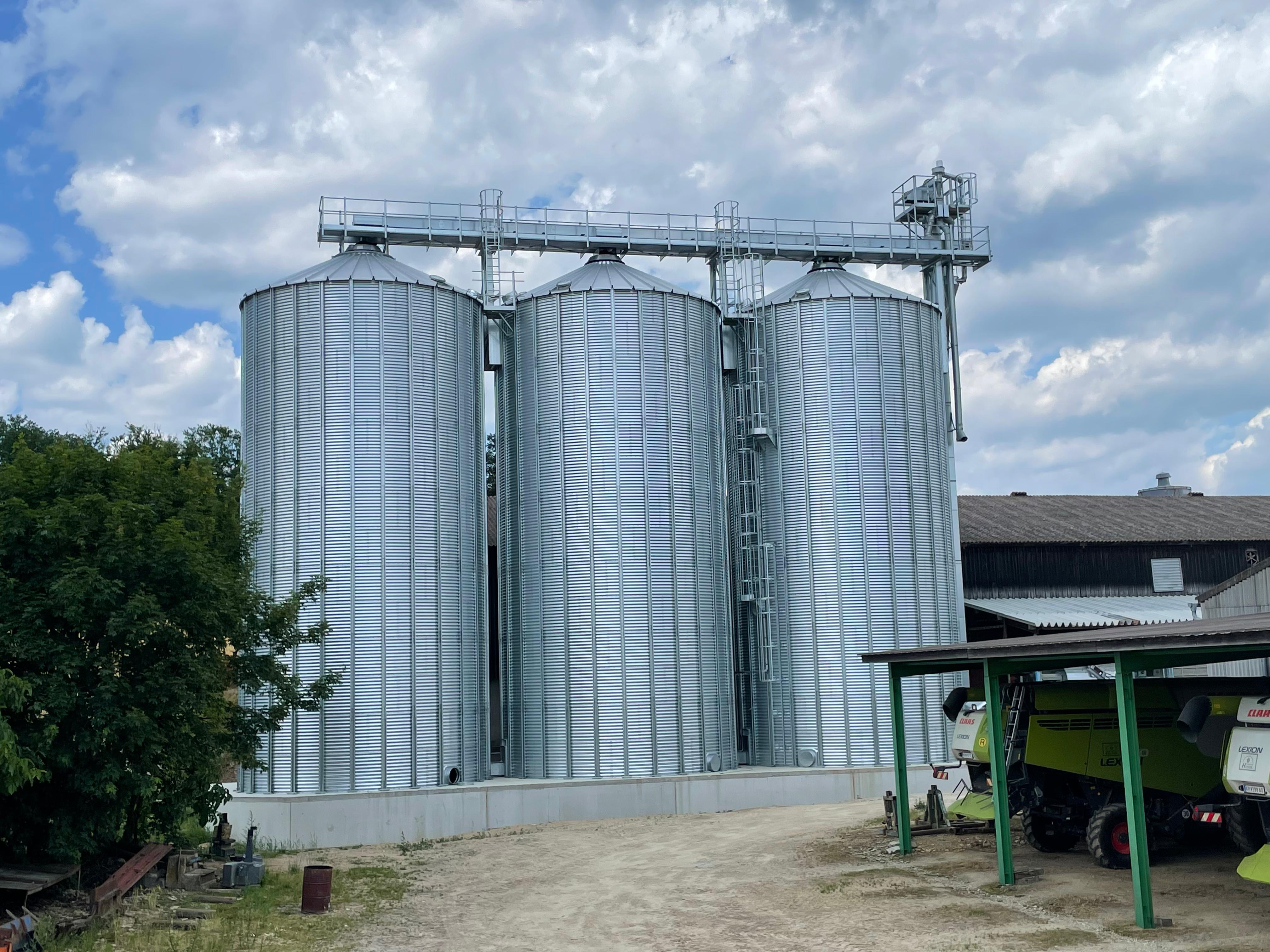 Drei Lagersilos mit Dachlaufsteg und Elevator auf einem landwirtschaftlichen Betrieb