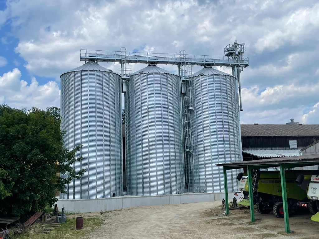 Drei große Wellblechsilos mit Förderbrücke auf Bauernhof