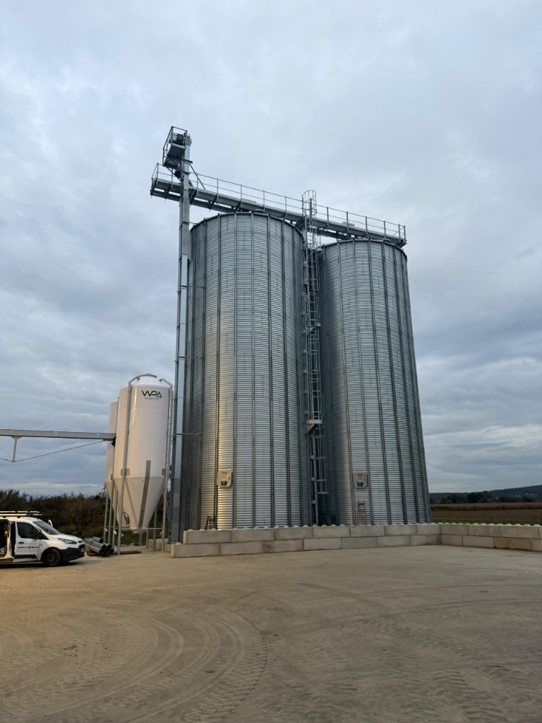Große Stahl-Lagersilos mit Fördertechnik und WPA-Firmenfahrzeug